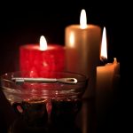 Ilustracja andrzejek - w tle trzy kolorowe palące się świece, przed nimi szklana misa, na której leży klucz, przed misą dwa małe gliniane kubeczki.